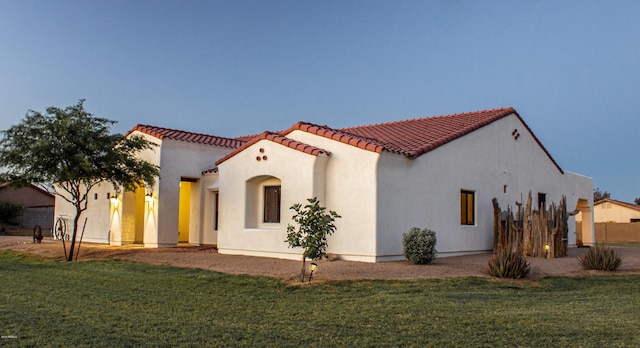 view of front of property featuring a tiled roof, a front lawn, and stucco siding