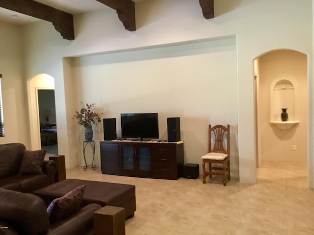 living room featuring arched walkways and beam ceiling