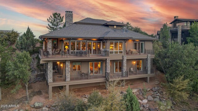 2800 E Morning Glory Cir, Payson, AZ 85541 - back of house at dusk featuring a balcony, a chimney, and stone siding