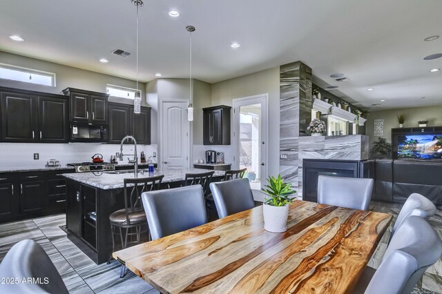 6215 E Sefton Dr, Prescott Valley, AZ 86314 - kitchen with visible vents, a kitchen island with sink, black microwave, dark cabinets, and open floor plan