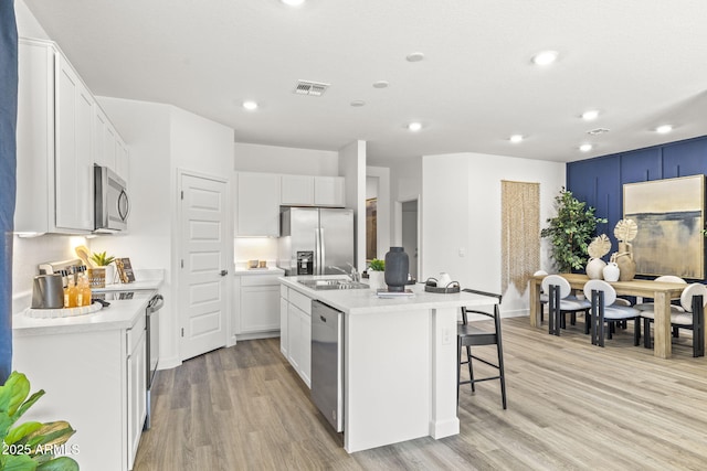 kitchen with stainless steel appliances, white cabinetry, a kitchen island with sink, and sink