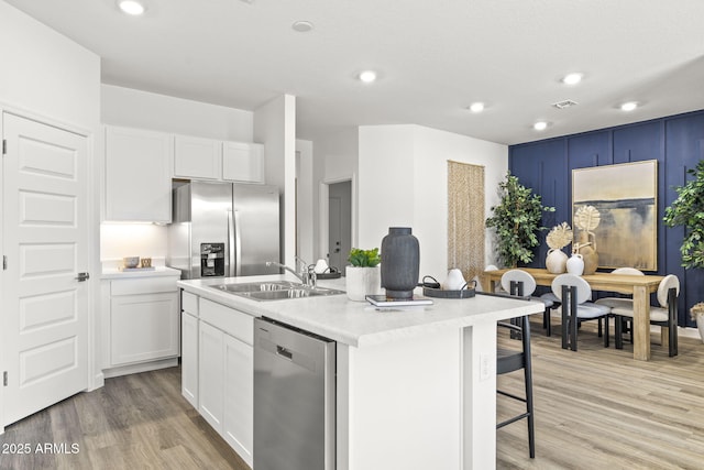 kitchen featuring white cabinetry, sink, stainless steel appliances, and a center island with sink