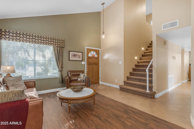 living room with visible vents, wood finished floors, stairway, high vaulted ceiling, and baseboards