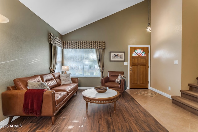 living room featuring baseboards, high vaulted ceiling, wood finished floors, and stairs