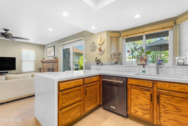 kitchen with light tile patterned flooring, a sink, dishwasher, a brick fireplace, and decorative backsplash