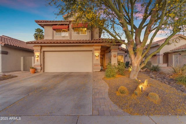 mediterranean / spanish-style home with a garage, stucco siding, concrete driveway, and a tile roof