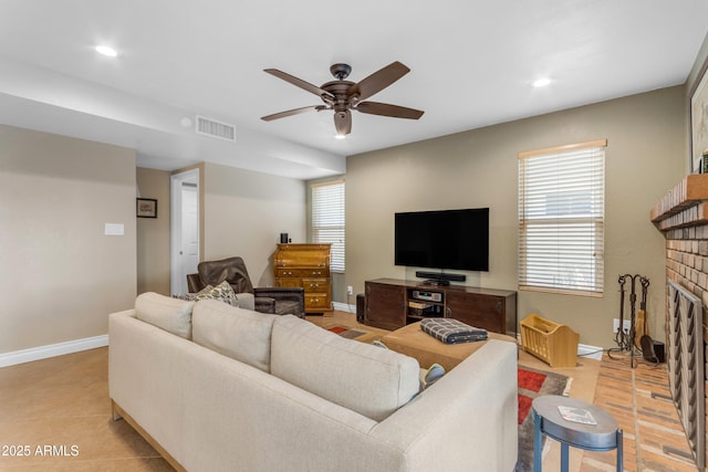 living room with visible vents, a ceiling fan, baseboards, and a fireplace