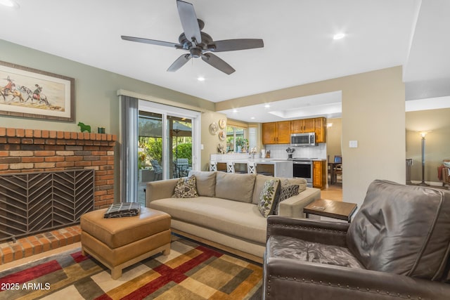living area with a ceiling fan, recessed lighting, and a brick fireplace