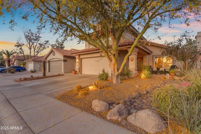 mediterranean / spanish-style home featuring an attached garage, driveway, a tile roof, and stucco siding