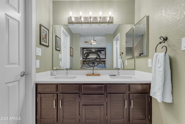 full bath with double vanity, a sink, and a textured wall