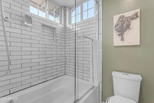 bathroom with a healthy amount of sunlight, bath / shower combo with glass door, and toilet