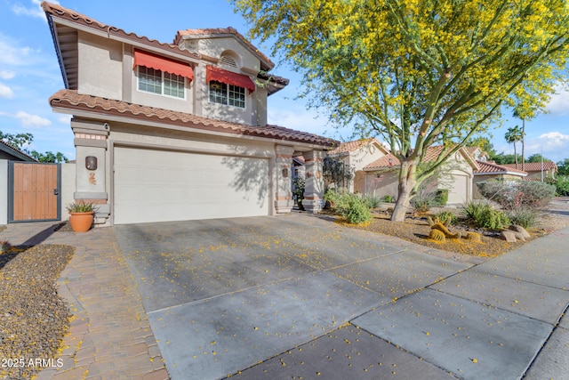 view of front of property with an attached garage, a tile roof, stucco siding, a gate, and concrete driveway