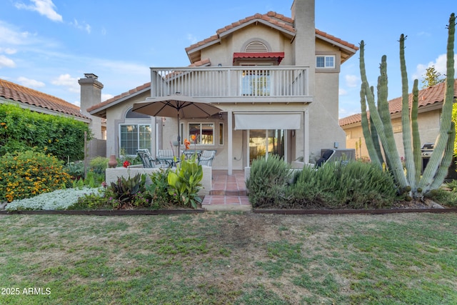 back of house with a tiled roof, a patio, a balcony, and stucco siding