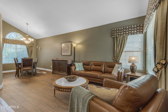 living area featuring an inviting chandelier, baseboards, wood finished floors, and lofted ceiling