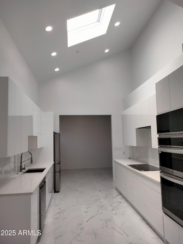 25150 N Windy Walk Dr Unit 14, Scottsdale, AZ 85255 - kitchen featuring modern cabinets, a high ceiling, a skylight, light marble finish flooring, and stainless steel appliances