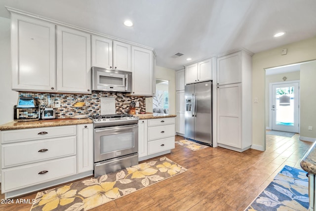 kitchen featuring appliances with stainless steel finishes, white cabinets, backsplash, and light hardwood / wood-style floors