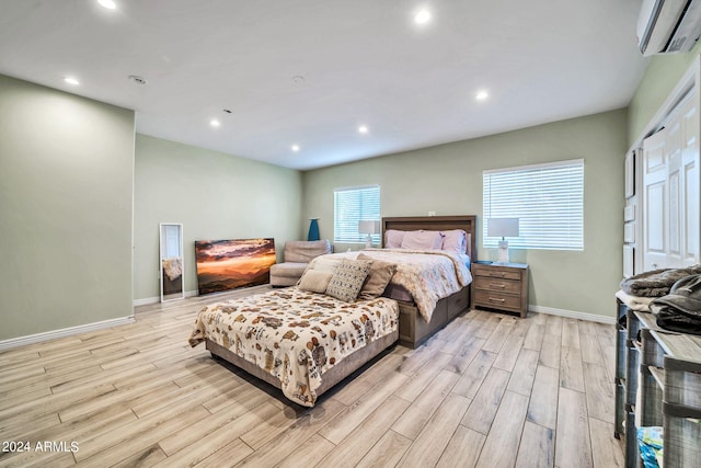 bedroom featuring a wall mounted AC and light wood-type flooring