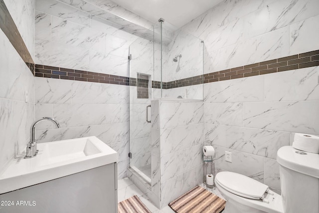 bathroom featuring a shower with door, toilet, tile walls, and vanity