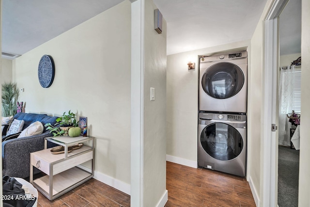 laundry room featuring stacked washer and dryer and dark hardwood / wood-style flooring