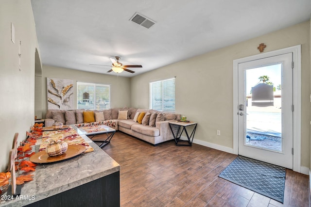 living room featuring dark hardwood / wood-style flooring, ceiling fan, and plenty of natural light