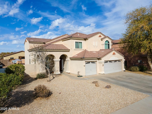 mediterranean / spanish house with driveway, stucco siding, a garage, and a tiled roof