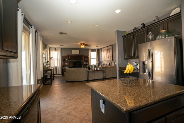 kitchen with light tile patterned floors, open floor plan, a center island, a fireplace, and stainless steel refrigerator with ice dispenser