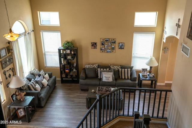 living room with a towering ceiling, baseboards, and wood finished floors