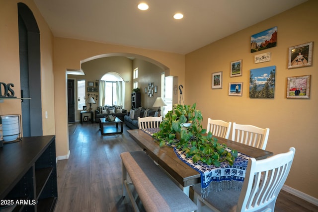 dining room with baseboards, arched walkways, dark wood-type flooring, and recessed lighting