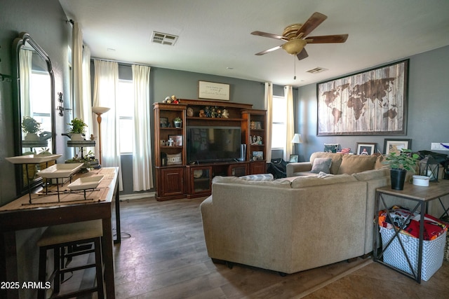 living area featuring visible vents, dark wood finished floors, and a ceiling fan