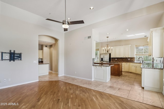 12183 E Mercer Ln, Scottsdale, AZ 85259 - kitchen featuring stainless steel fridge, tasteful backsplash, a chandelier, light wood-type flooring, and dark stone countertops