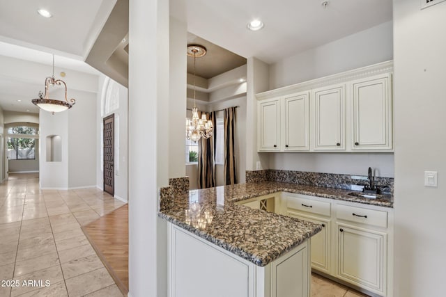 12183 E Mercer Ln, Scottsdale, AZ 85259 - kitchen with dark stone countertops, a sink, a chandelier, a peninsula, and recessed lighting