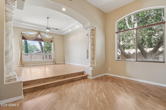 12183 E Mercer Ln, Scottsdale, AZ 85259 - empty room featuring ornate columns, arched walkways, wood finished floors, baseboards, and a ceiling fan