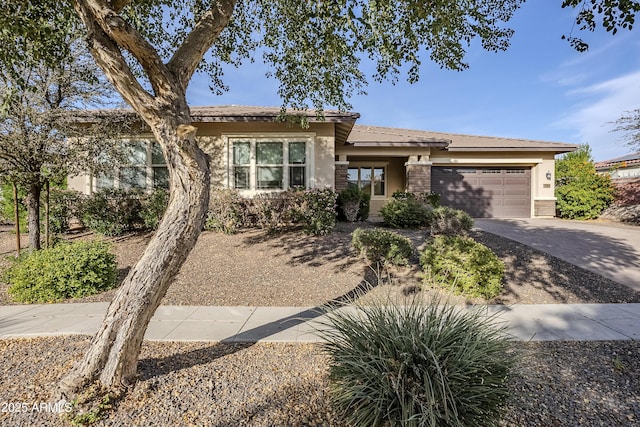 view of front of property with a garage, brick siding, driveway, and stucco siding