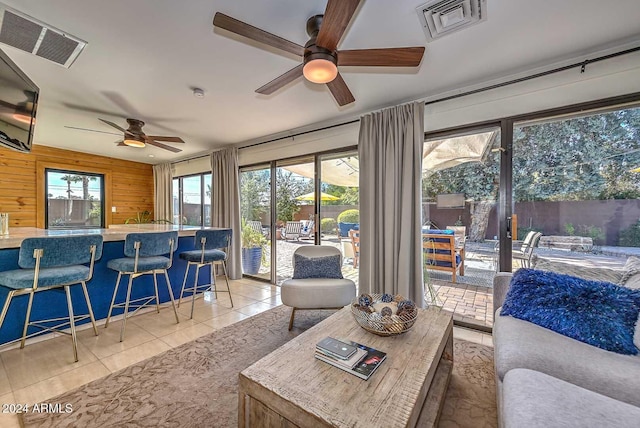 tiled living room featuring ceiling fan and wooden walls