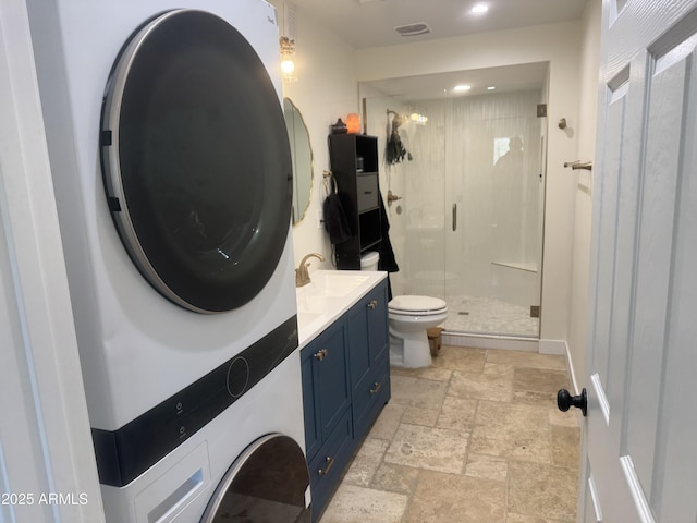 bathroom featuring vanity, stacked washer and dryer, toilet, and a shower with shower door