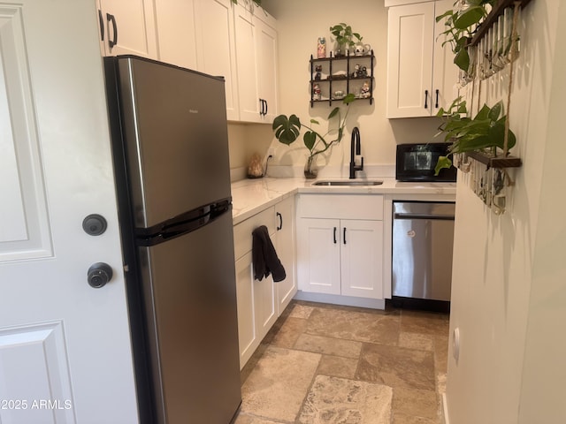 kitchen featuring light stone countertops, sink, white cabinetry, and stainless steel appliances