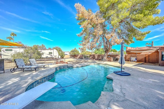 view of pool with a diving board and a patio area