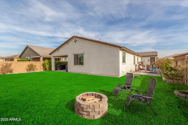 back of house featuring an outdoor fire pit and a yard