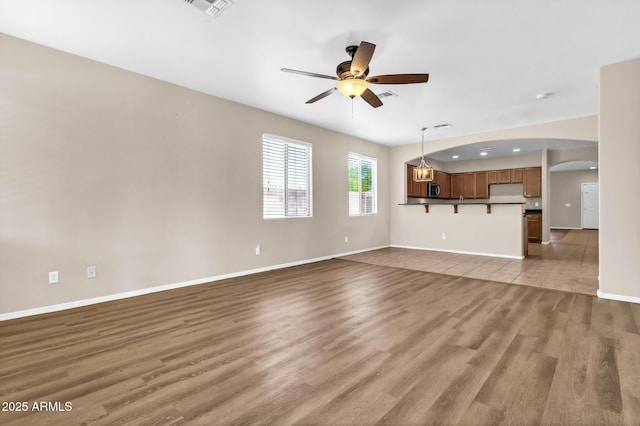 209 E Diamond Trl, San Tan Valley, AZ 85143 - unfurnished living room with ceiling fan, arched walkways, wood finished floors, and baseboards