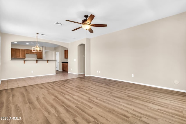 209 E Diamond Trl, San Tan Valley, AZ 85143 - unfurnished living room featuring arched walkways, light wood-style flooring, ceiling fan, and baseboards
