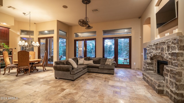 living room with a high ceiling, a stone fireplace, and an inviting chandelier