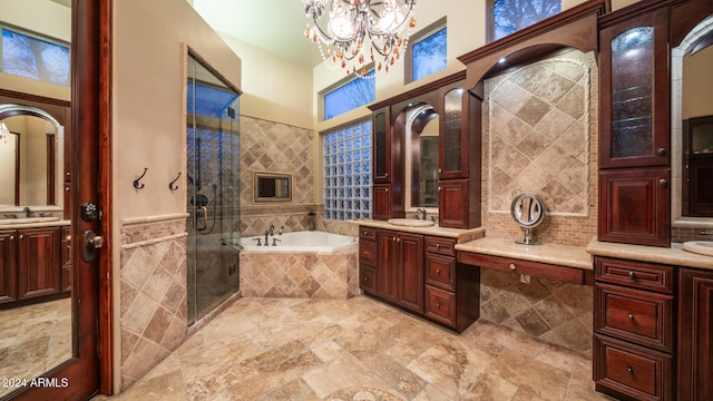 bathroom with an inviting chandelier, vanity, plus walk in shower, and tile walls