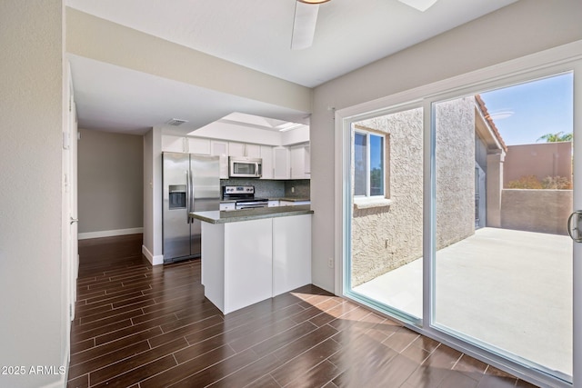 18548 E Parada Cir, Rio Verde, AZ 85263 - kitchen with dark wood finished floors, a peninsula, white cabinetry, appliances with stainless steel finishes, and dark countertops