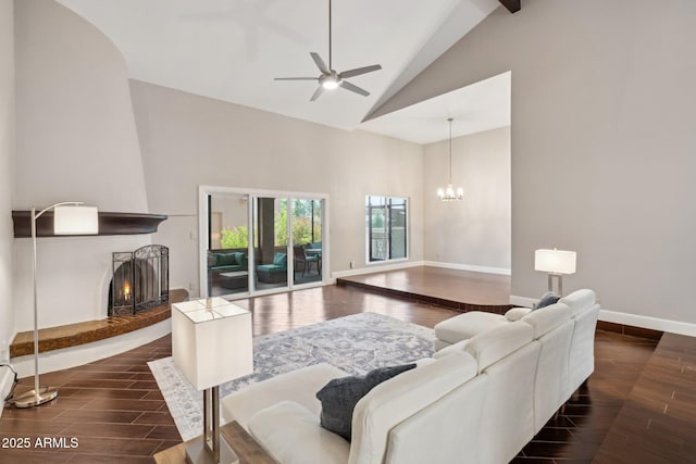 18548 E Parada Cir, Rio Verde, AZ 85263 - living room featuring ceiling fan with notable chandelier, high vaulted ceiling, a large fireplace, wood finished floors, and baseboards