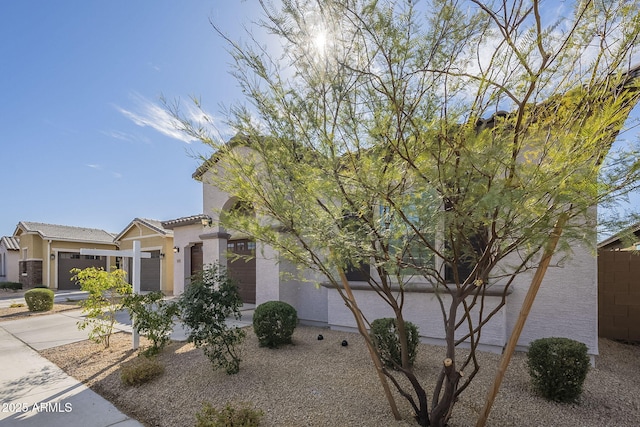 view of front of home featuring an attached garage, a tiled roof, concrete driveway, and stucco siding