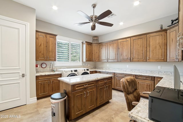 kitchen featuring a center island, separate washer and dryer, light stone counters, and ceiling fan