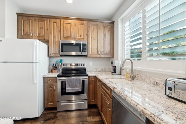 kitchen with light stone countertops, appliances with stainless steel finishes, dark hardwood / wood-style floors, and sink