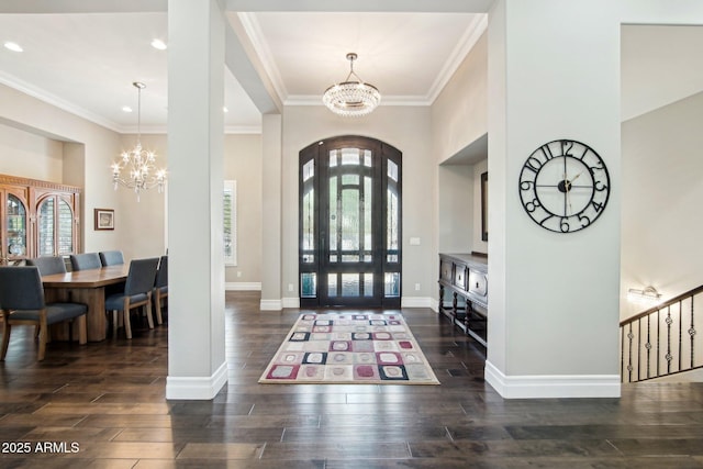 entryway featuring a chandelier, dark wood-type flooring, and ornamental molding