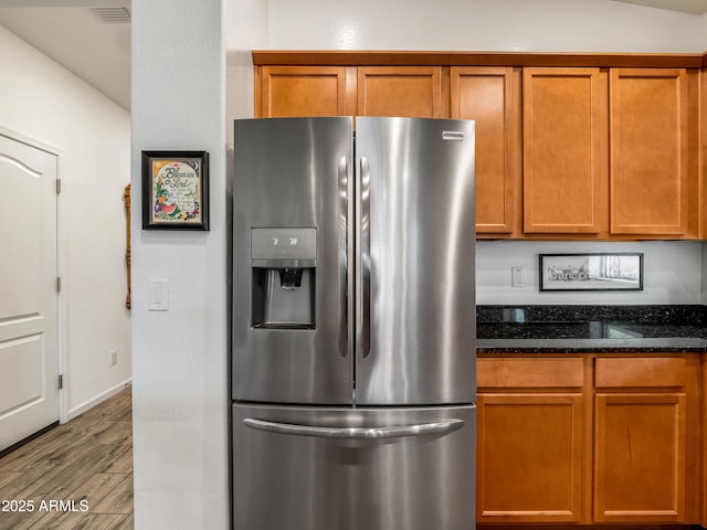 7648 S Thimble Peak, Gold Canyon, AZ 85118 - kitchen with stainless steel refrigerator with ice dispenser, wood finished floors, brown cabinetry, and dark stone counters