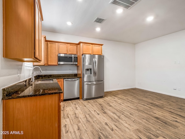 7648 S Thimble Peak, Gold Canyon, AZ 85118 - kitchen featuring appliances with stainless steel finishes, a sink, light wood-style floors, dark stone countertops, and baseboards